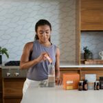 a woman in a kitchen making a drink
